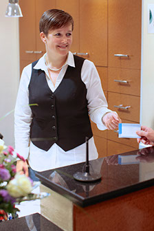 Mitarbeiterin am Empfang nimmt Dokument eines Patienten in die Hand